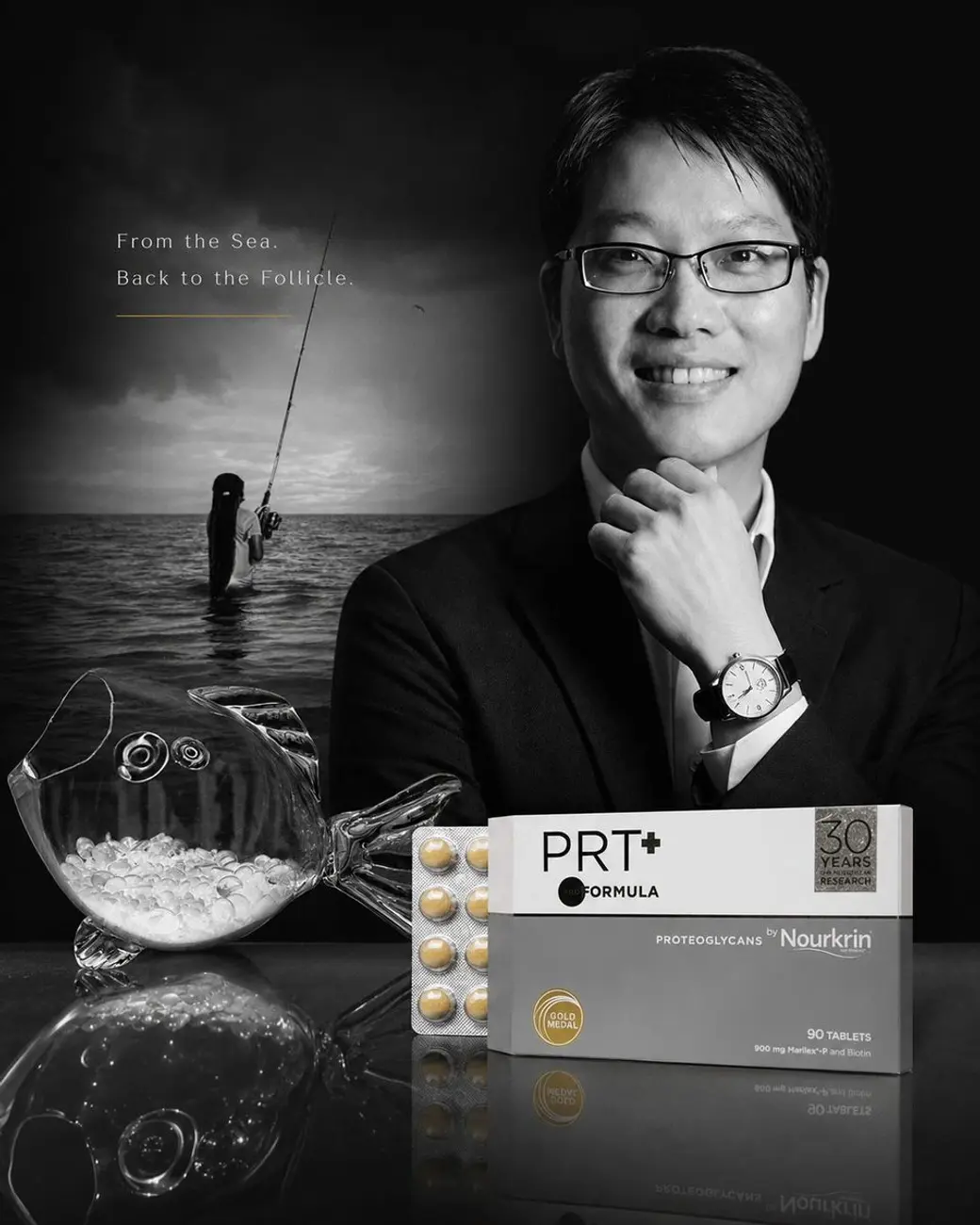 廠商形象圖，黑白背景中一位戴眼鏡的男性托著下巴微笑，左側是海上釣客的剪影，前方放著一個裝著顆粒的玻璃器皿與一盒錠劑產品，上方寫著 From the Sea. Back to the Follicle.。