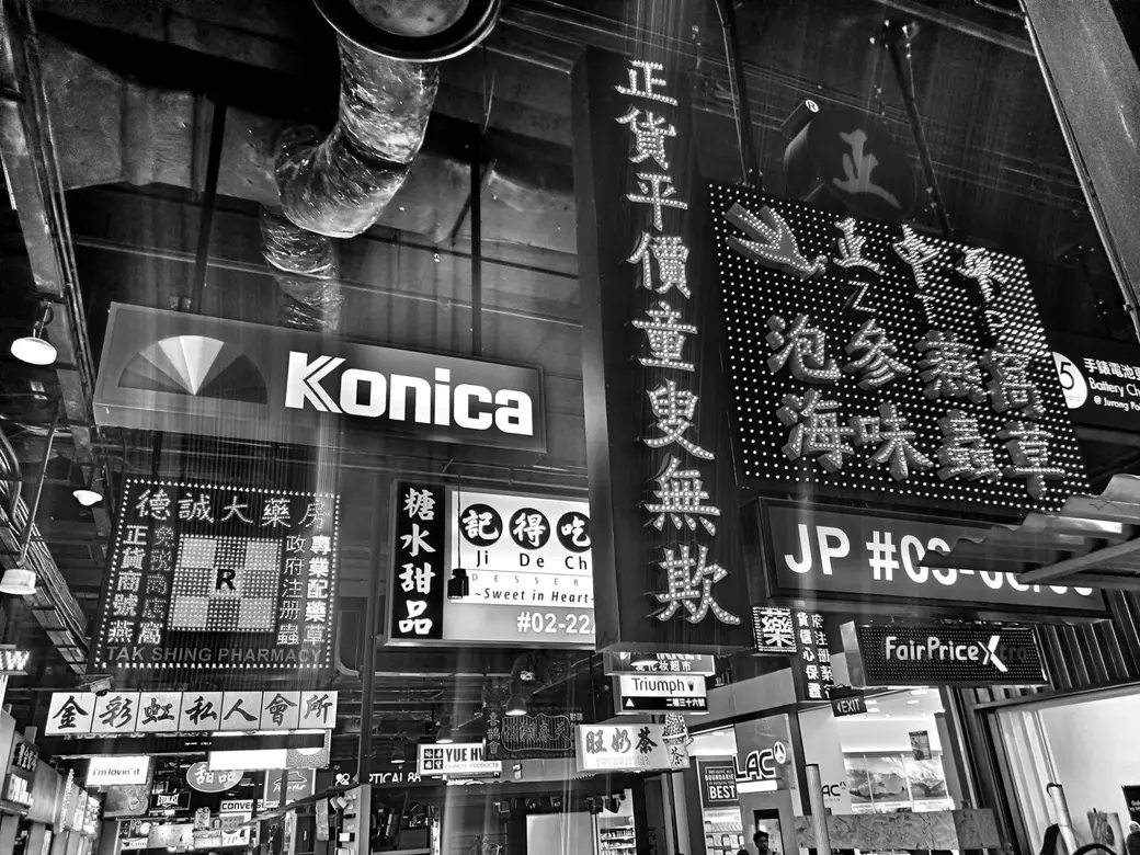 一整面密密麻麻、彼此擠壓的店家招牌，黑白影像。